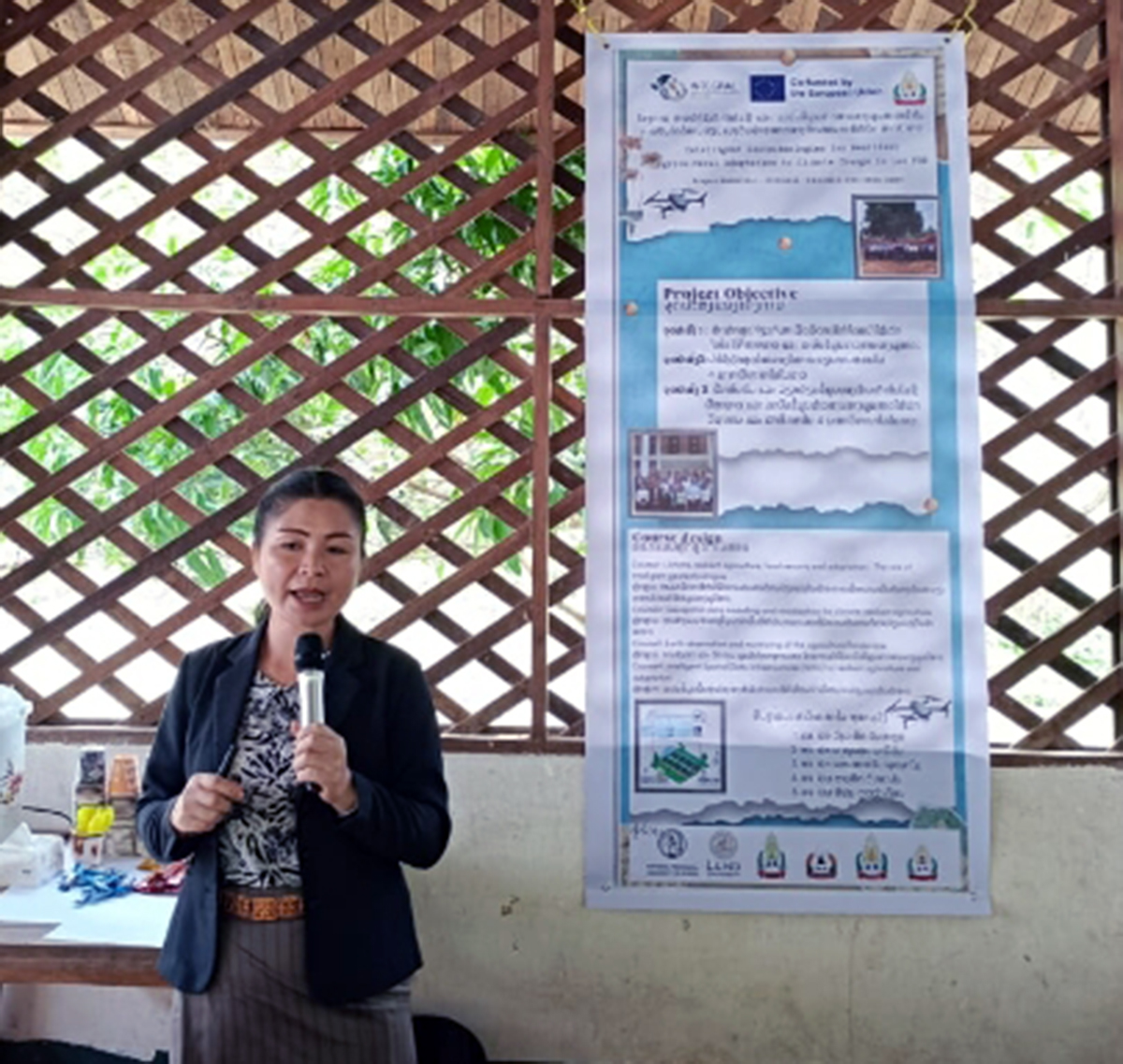 A speaker holding a microphone in front of a poster