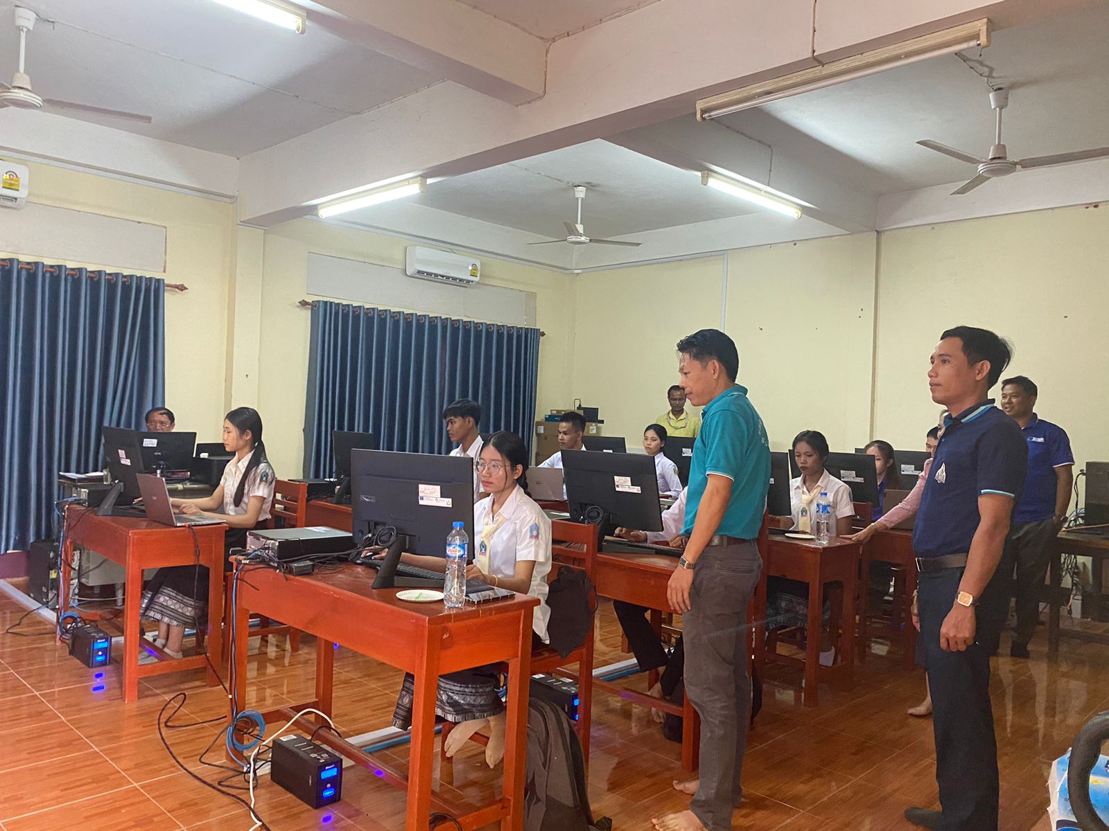 Students working in a computer lab, supervised by instructors