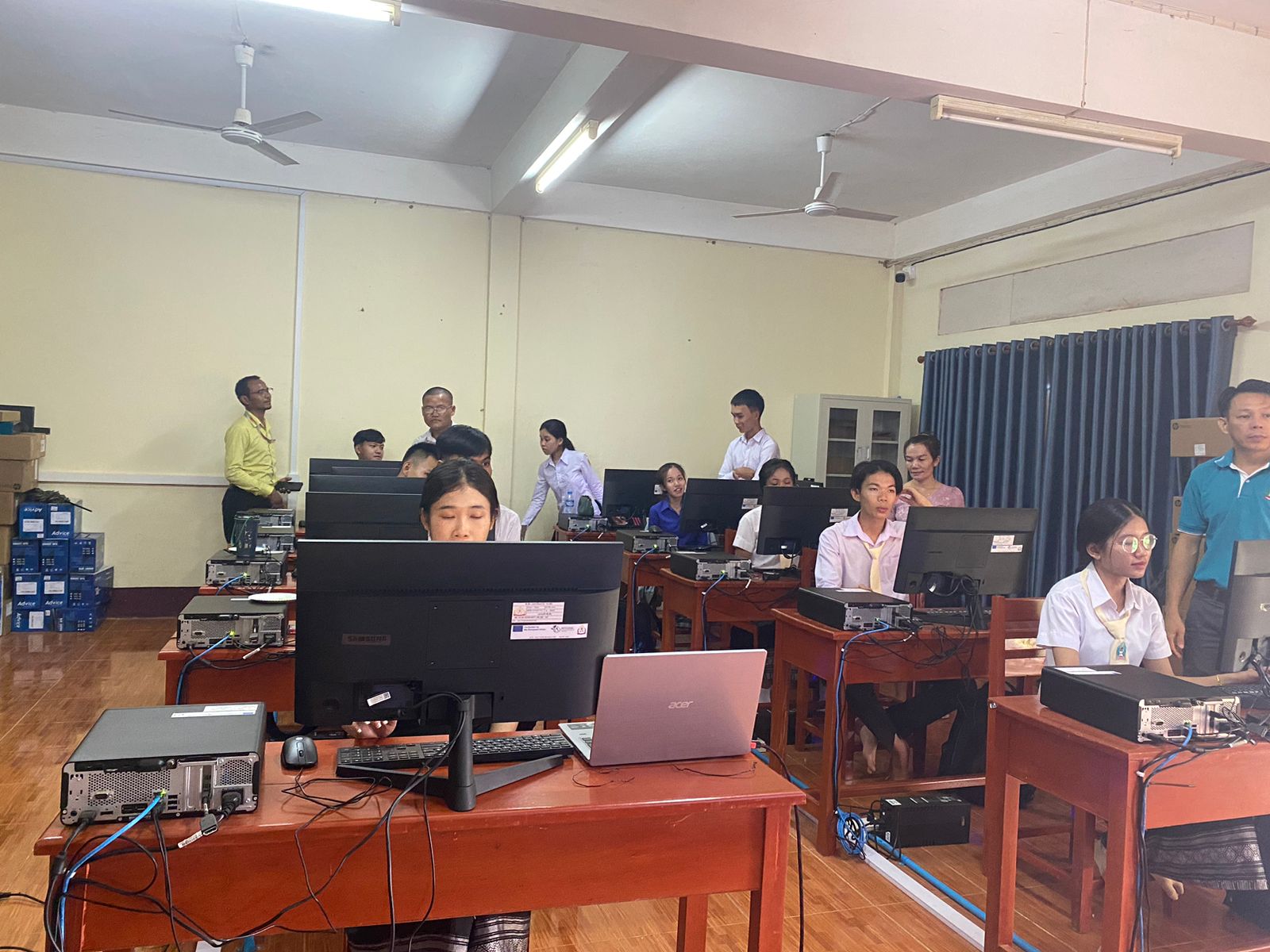 Students working in a computer lab, supervised by instructors