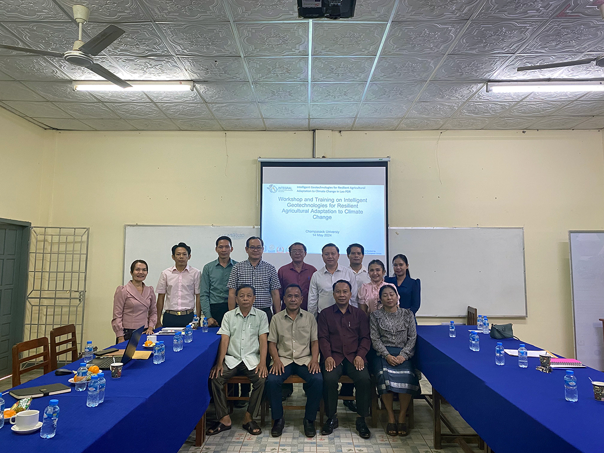 A group photo of people standing in front of a slideshow in a meeting room