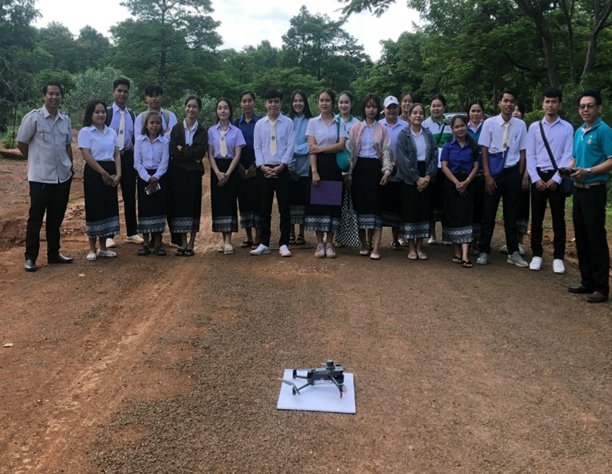 A group of students outdoors, looking at a drone